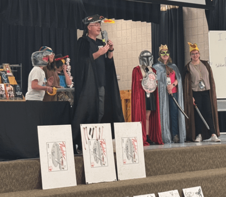 Author Johan Twiss, 5th grade teachers, and 3 5th grade students on stage dressed up in costumes